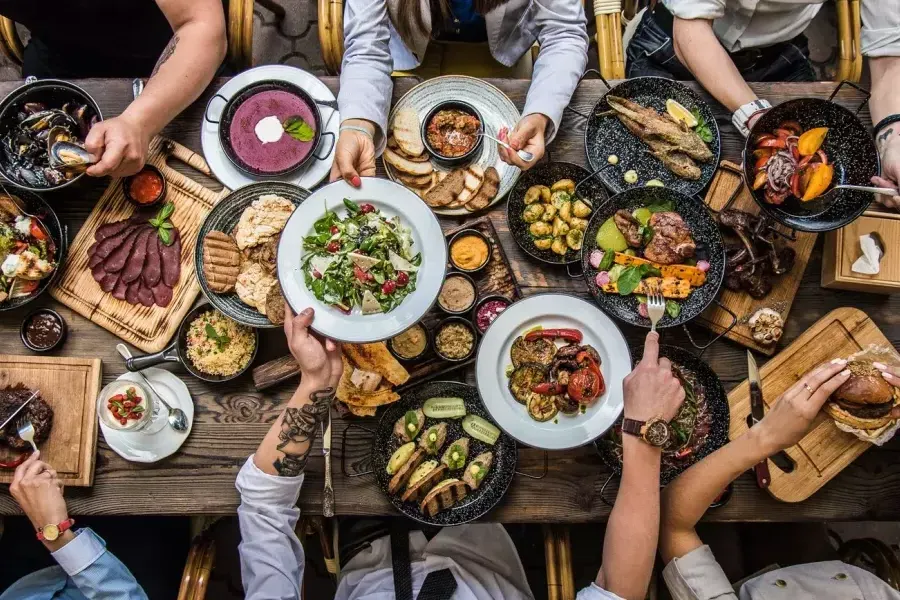 People sitting at a dining table, sharing food.